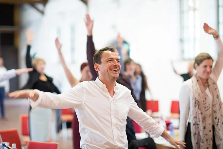 Teilnehmer eines Smart Business Seminars nehmen aktiv und lachend teil.